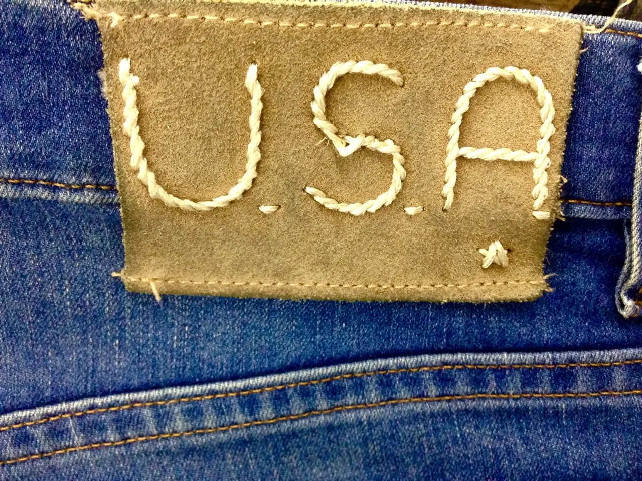 There is a blue color jeans. On the jeans there is a label with something written on it.