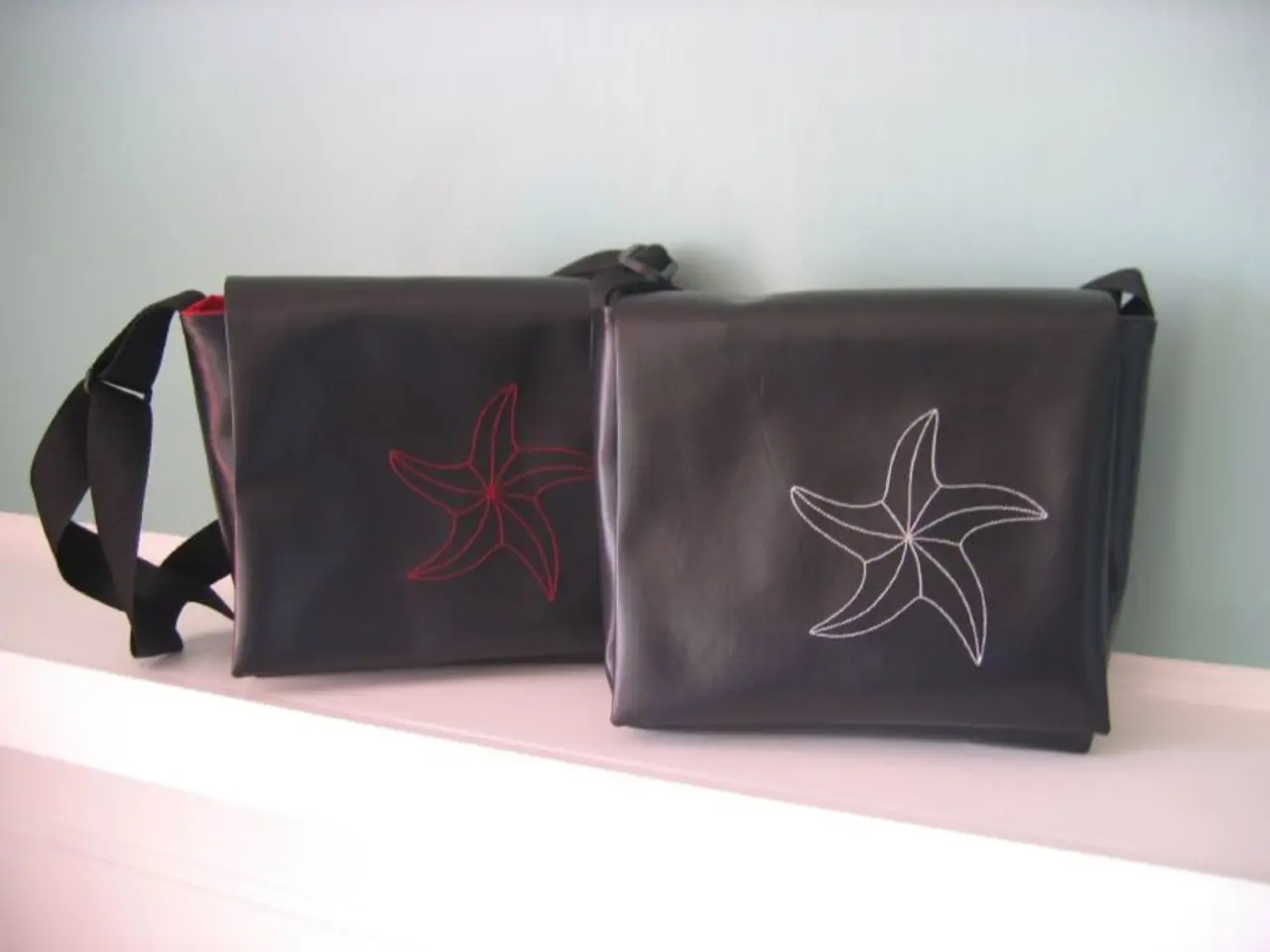 There are two hand bags in a shelf and the bags has a flower symbol on it.