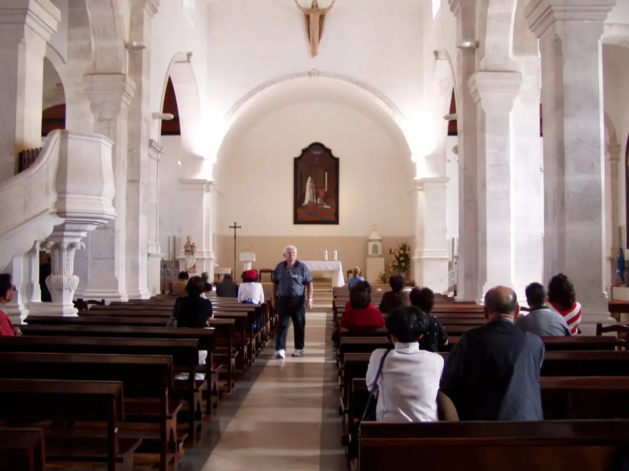 In the image there are few people sitting on benches on either side, in the middle there is an old...