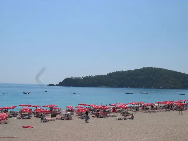 In the picture i can see some group of persons sitting on sea benches under umbrellas and some are...