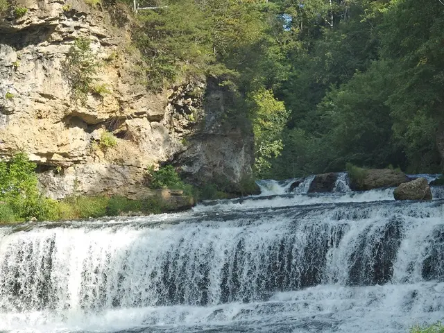 In the picture there is a flowing river and in the left side there is a hill and there are many...