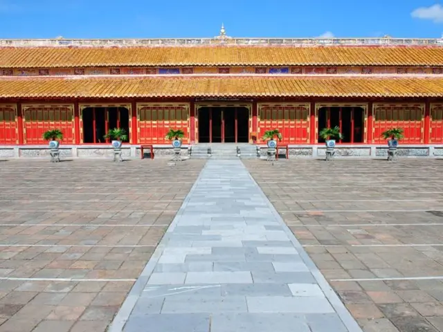 In this picture I can see a building, there are flower pots with plants on the stools, and in the...