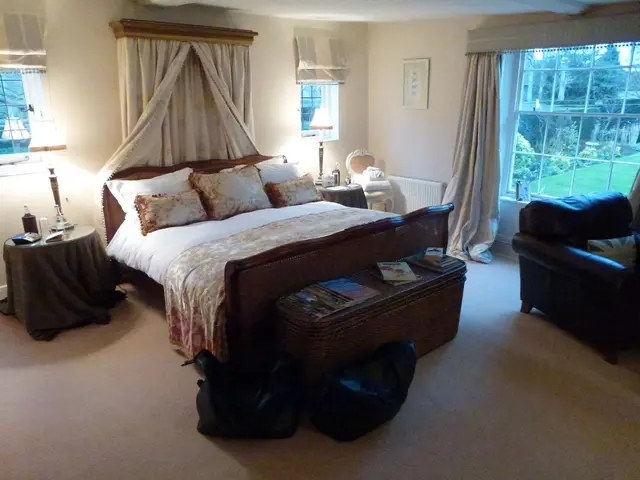 In this image there are chairs, books, glass, bottle and some objects on the tables, blankets and...