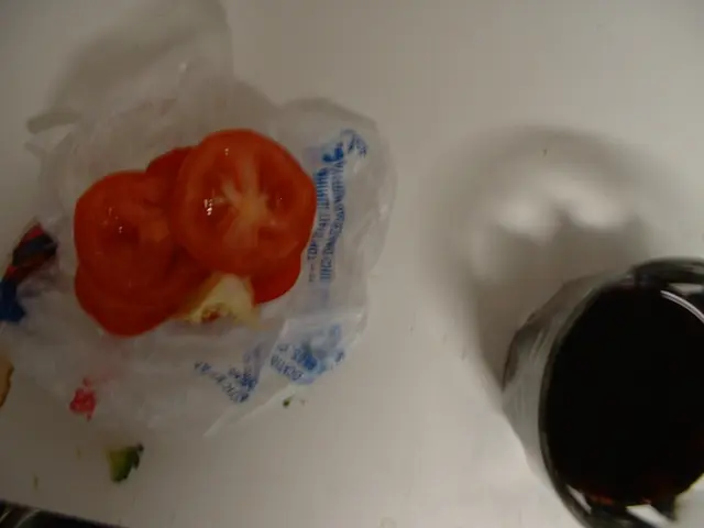 In this picture there are few sliced tomatoes placed on a plastic cover and there is a glass of...